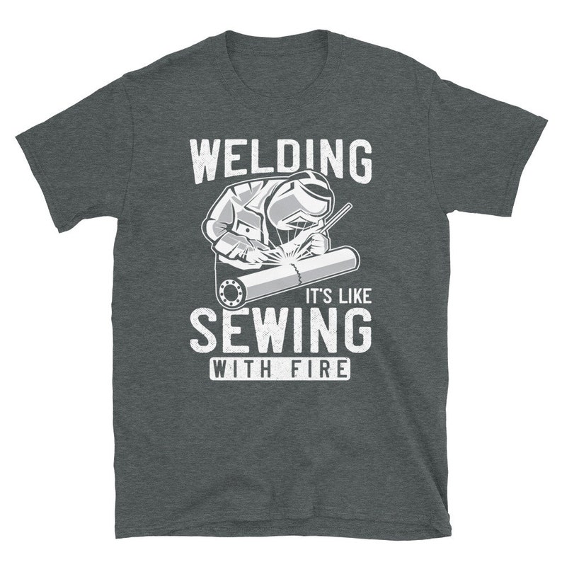May include: A dark gray t-shirt with a white graphic of a welder and the text "Welding It's Like Sewing With Fire".