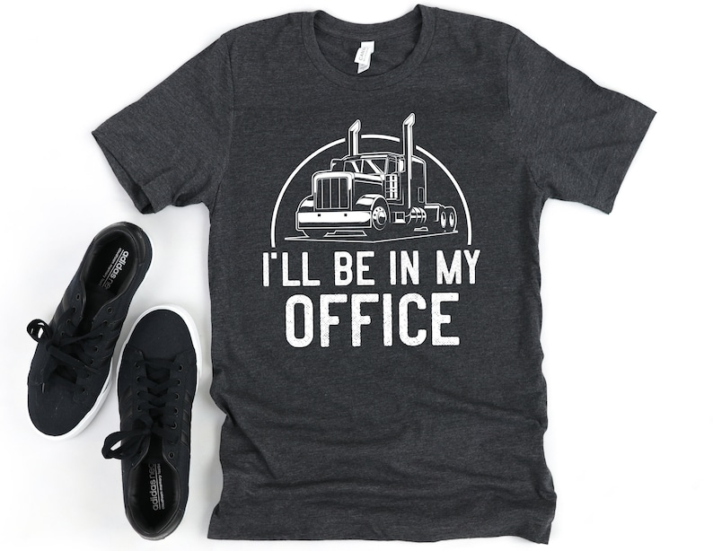 May include: A dark gray t-shirt with a white graphic of a semi-truck and the text "I'll be in my office".