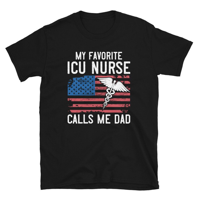 May include: Black t-shirt with a white American flag and a medical caduceus symbol. The text "My Favorite ICU Nurse Calls Me Dad" is printed on the shirt.