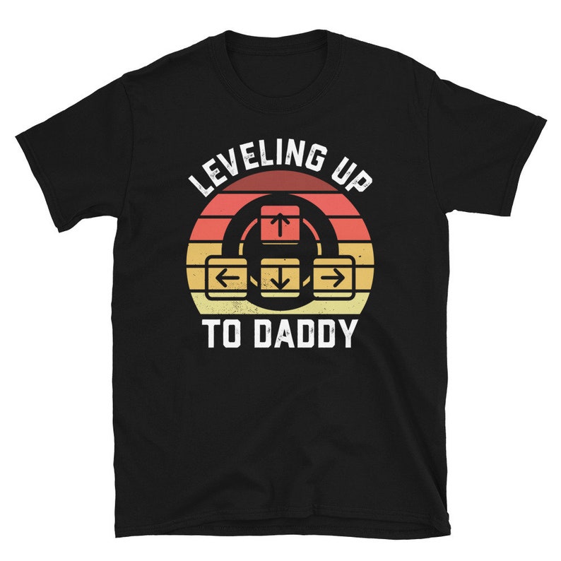 May include: Black t-shirt with a retro-style graphic that says "Leveling Up To Daddy" with an arrow key design.