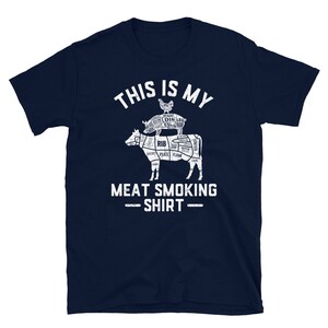 May include: Navy blue t-shirt with a white graphic of a cow and pig with labeled cuts of meat. The text "This is my meat smoking shirt" is printed below the graphic.
