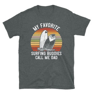 Może przedstawiać: Szary t-shirt z białym nadrukiem graficznym. Grafika przedstawia zach&oacute;d słońca z dwoma deskami surfingowymi i tekstem "My Favorite Surfing Buddies Call Me Dad."