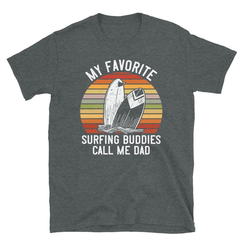 Może przedstawiać: Szary t-shirt z białym nadrukiem graficznym. Grafika przedstawia zach&oacute;d słońca z dwoma deskami surfingowymi i tekstem "My Favorite Surfing Buddies Call Me Dad."