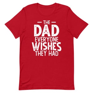 May include: Red short-sleeved t-shirt with white text that reads "The Dad Everyone Wishes They Had".