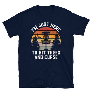 May include: A navy blue t-shirt with a vintage-style graphic of a disc golf basket and the text "I'm Just Here To Hit Trees And Curse".