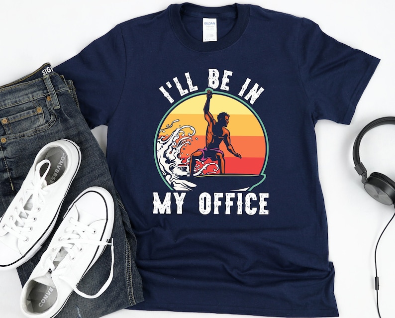 May include: A navy blue t-shirt with a white graphic of a person surfing with the text "I'll be in my office".