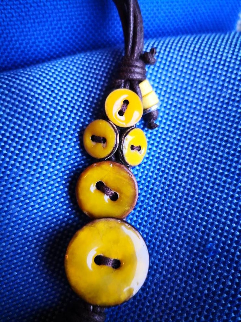 Necklace of yellow coconut wood buttons sewn on a dark brown waxed cotton drawstring.