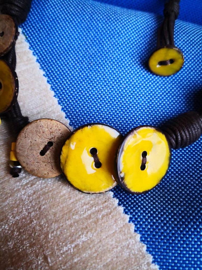 Necklace of yellow coconut wood buttons sewn on a dark brown waxed cotton drawstring.