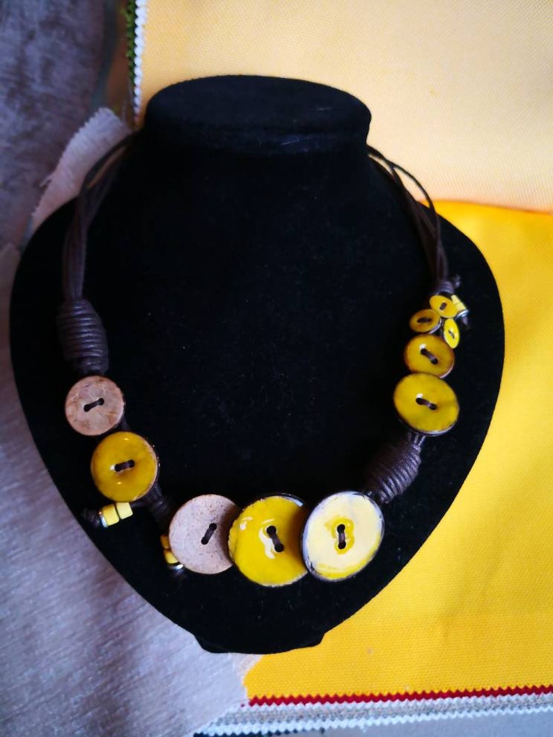 Necklace of yellow coconut wood buttons sewn on a dark brown waxed cotton drawstring.
