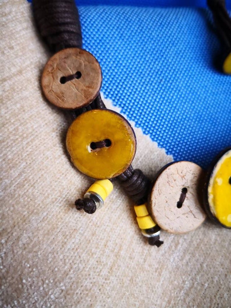 Necklace of yellow coconut wood buttons sewn on a dark brown waxed cotton drawstring.