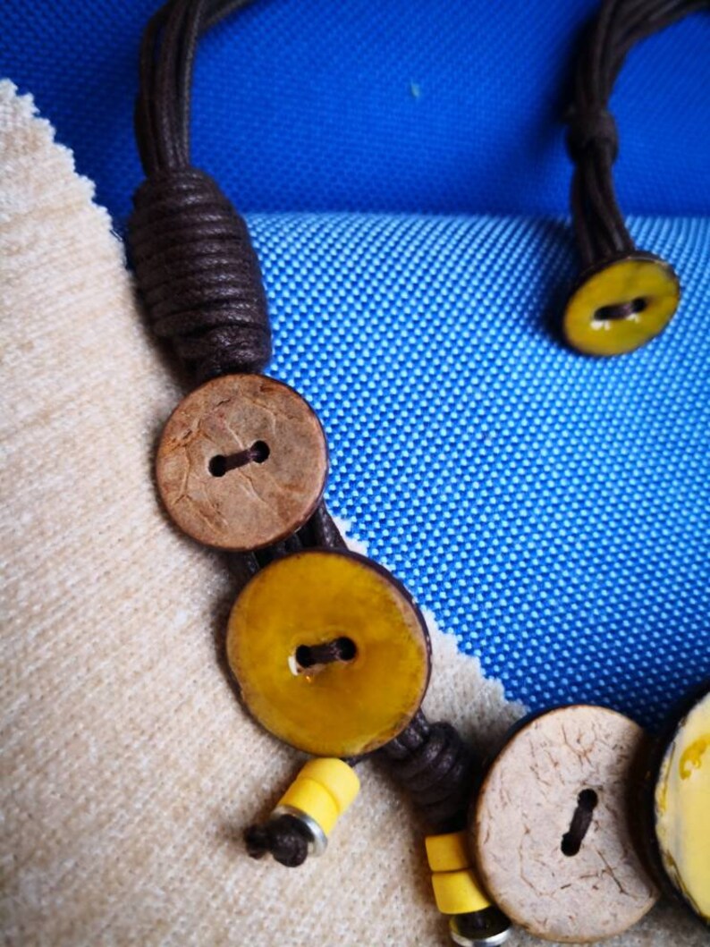 Necklace of yellow coconut wood buttons sewn on a dark brown waxed cotton drawstring.