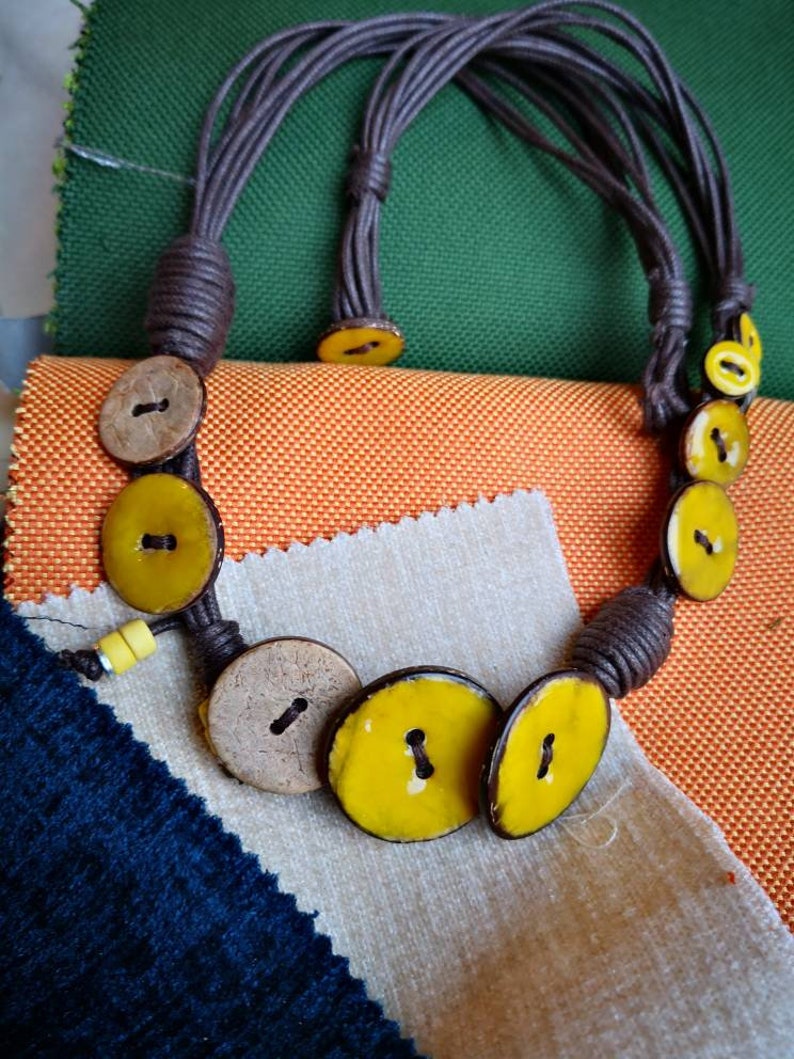 Necklace of yellow coconut wood buttons sewn on a dark brown waxed cotton drawstring.