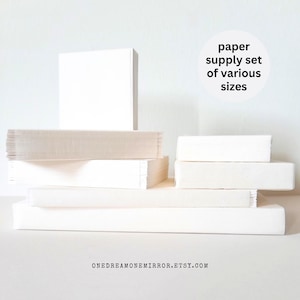 May include: A collection of white paper stacks and pads of various sizes. The image includes a large square stack, several rectangular pads, and a few smaller stacks, all in shades of white. Text on the image reads: "paper supply set of various sizes."