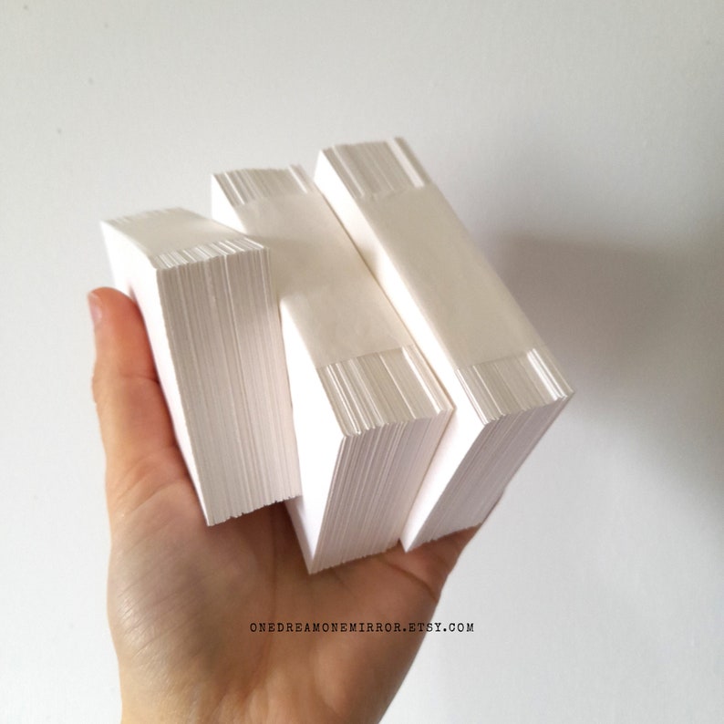 May include: Three stacks of white paper, held in a hand, are shown against a white background. Each stack is rectangular and bound with a white band. The paper appears to be clean and unused. The Etsy shop name is visible at the bottom.