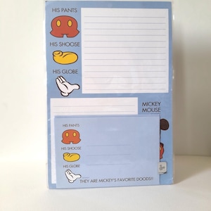 Op de afbeelding: Een lichtblauwe notitieblok- en envelopset met Mickey Mouse-afbeeldingen. Het briefpapier toont iconen voor HIS PANTS, HIS SHOOSE en HIS GLOBE, met de tekst MICKEY MOUSE en THEY ARE MICKEY'S FAVORITE DOODS!! op de items gedrukt.
