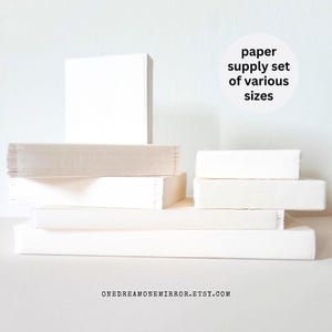 May include: A collection of white paper stacks and pads of various sizes. The image includes a tall, square stack, several rectangular pads, and a few smaller stacks. Text on the image reads: "paper supply set of various sizes."