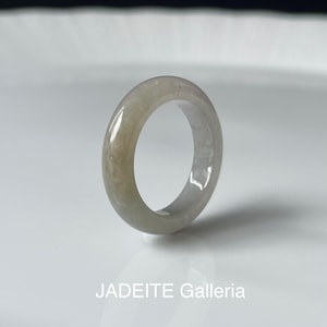 May include: A light green jadeite ring with a smooth, polished surface. The ring is a solid band with a circular shape. The text "JADEITE Galleria" is at the bottom of the image.