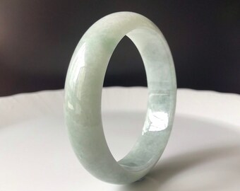 May include: A light green jade bangle bracelet. The bangle is smooth and polished, with a subtle sheen.