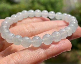 Könnte beinhalten: Ein hellblaues Jadeit-Armband mit runden Perlen. Das Armband ist aus natürlichem Jadeit gefertigt und ein wunderschönes Beispiel für diesen Edelstein.