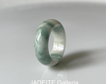 May include: A jade ring with a marbled appearance, featuring shades of green and white. The ring is smooth and polished, with a rounded shape. The text "JADEITE Galleria" is visible at the bottom of the image.