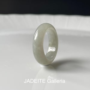 May include: A light green jadeite ring with a polished, glossy finish. The ring is a solid band with a smooth surface. The text "JADEITE Galleria" is at the bottom of the image.