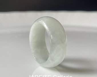 May include: A white jadeite ring with a smooth, polished finish. The ring is thick and has a wide band.
