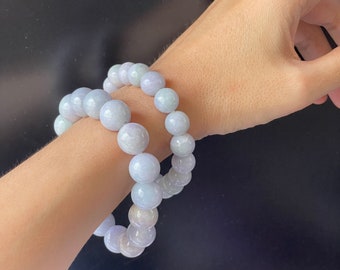 May include: Two lavender jade bead bracelets on a person's wrist. The beads are round and smooth.