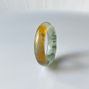 May include: A green and yellow agate ring with a polished finish. The ring is made of natural stone and has a unique pattern.