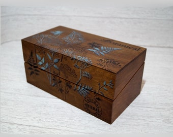 May include: A wooden box with a hinged lid, decorated with a botanical print in shades of brown and blue. The box has the word "Botanical" printed on the top and "Natural Herbal" on the side.