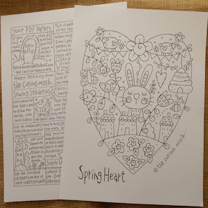 Op de afbeelding: Een zwart-witte lijntekening van een hartvormig ontwerp met een konijn, huizen, bloemen, vogels en bijen. De tekst "Spring Heart" staat onder het ontwerp. De tekst "the curious missb..." staat in de rechterbenedenhoek van het ontwerp.