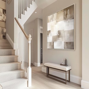 May include: An interior hallway featuring a staircase, artwork, and a bench. The staircase has white balusters and a light wood handrail. A large abstract painting in neutral tones hangs above a bench with a cream cushion and a dark metal frame.