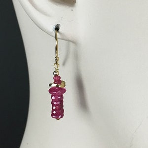 May include: Gold earrings with a dangling pink gemstone cluster.
