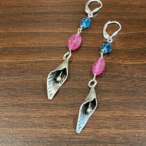 May include: Silver earrings with pink and blue gemstone beads and a silver flower charm.
