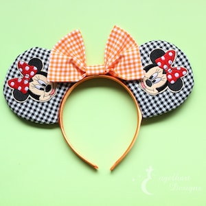 Könnte beinhalten: Minnie-Mouse-Ohren-Haarreif mit schwarz-weiß karierten Ohren, einer orangefarbenen Vichy-Schleife und einer Minnie-Mouse-Applikation. Das Stirnband ist orange. Die Ohren haben eine rote Schleife mit Punkten.