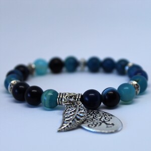 May include: A blue and black beaded bracelet with a silver charm featuring a leaf and the word "Believe".