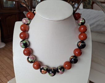May include: A necklace made of red and black beads with floral designs. The beads are round and have a glossy finish.