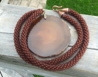 May include: A brown beaded necklace with a large, round, brown agate pendant.