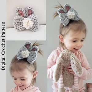 K&ouml;nnte beinhalten: Ein grauer geh&auml;kelter Hasenbogen mit rosa Ohren und einem wei&szlig;en Bommel. Der Bogen wird von einem kleinen Kind mit braunen Haaren getragen.