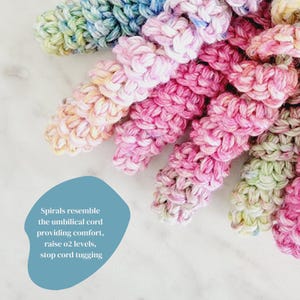 Puede incluir: Primer plano de varias espirales coloridas tejidas a mano en tonos rosa, azul, amarillo y verde. El texto de la imagen dice: "Las espirales se asemejan al cord&oacute;n umbilical que proporciona comodidad, eleva los niveles de o2, detiene el tir&oacute;n del cord&oacute;n."
