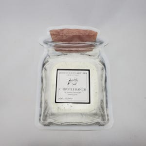 Può includere: Un barattolo di vetro trasparente con coperchio in sughero, riempito con una polvere bianca. Il barattolo ha un'etichetta con la scritta "Chipotle Ranch" e "Branch Root Forest Farm". Il peso netto è di 28,3 grammi.