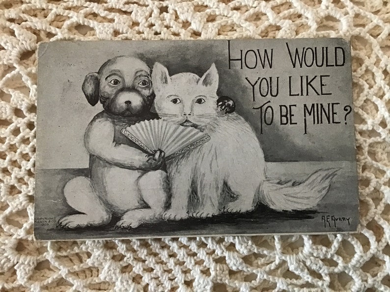 May include: Black and white vintage postcard featuring a dog and cat with a hand fan. The text on the postcard reads "How would you like to be mine?"