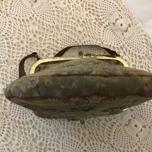 K&ouml;nnte beinhalten: Eine Vintage-Handtasche aus Tapisserie-Stoff mit einem goldfarbenen Verschluss und einem braunen Lederriemen.