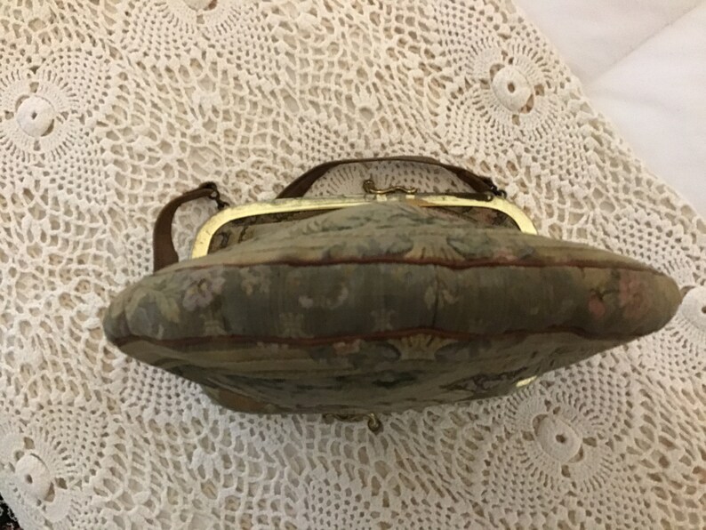 K&ouml;nnte beinhalten: Eine Vintage-Handtasche aus Tapisserie-Stoff mit einem goldfarbenen Verschluss und einem braunen Lederriemen.