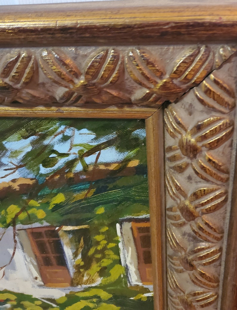 Puede incluir: Una pintura al &oacute;leo enmarcada que representa una caba&ntilde;a con un exterior blanco y puertas de madera marr&oacute;n. La caba&ntilde;a est&aacute; rodeada de exuberante vegetaci&oacute;n verde y &aacute;rboles. El marco es de color dorado con un dise&ntilde;o decorativo.