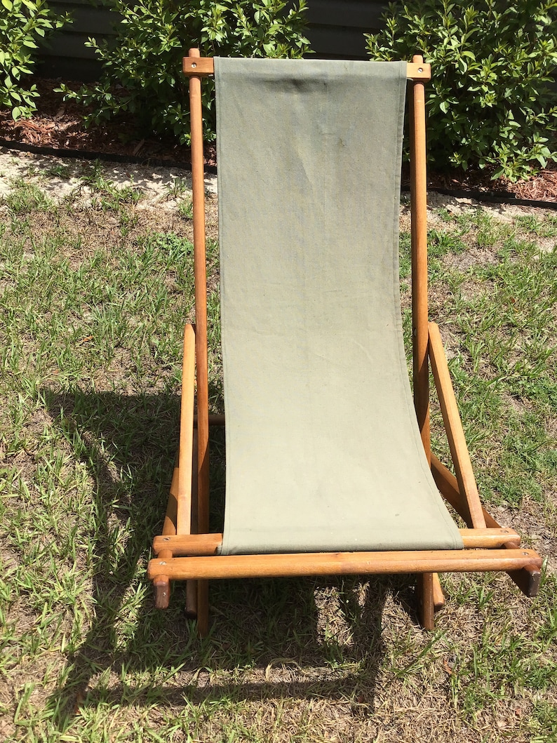 May include: A wooden folding chair with a green canvas seat and back. The chair is in a grassy area.