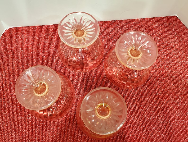 May include: Four pink glass dessert dishes with a textured pattern. The dishes are upside down, showing the bottom of the dishes.
