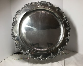 May include: A large, round, silver serving tray with an ornate, embossed grapevine design around the edge.