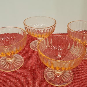 May include: Four clear glass dessert cups with a fluted design and a short stem. The cups are a pale yellow color.