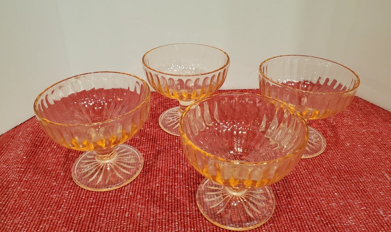 May include: Four clear glass dessert cups with a fluted design and a short stem. The cups are a pale yellow color.