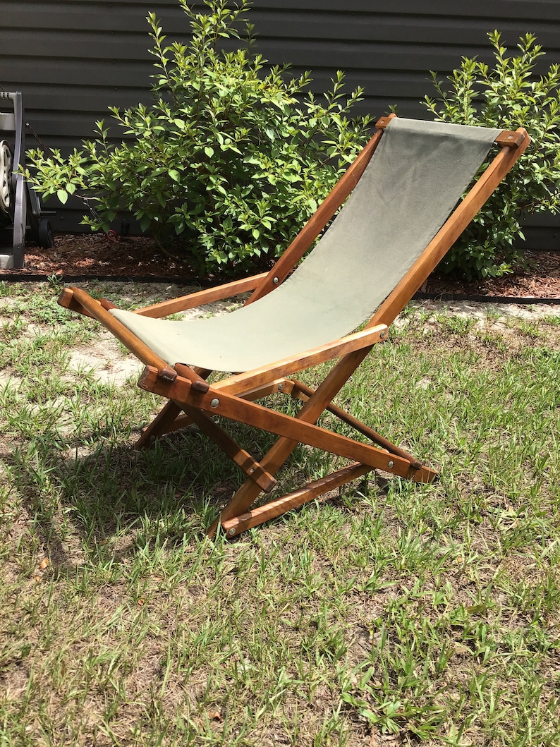 May include: A wooden folding chair with a canvas seat and back. The chair is in a grassy area.